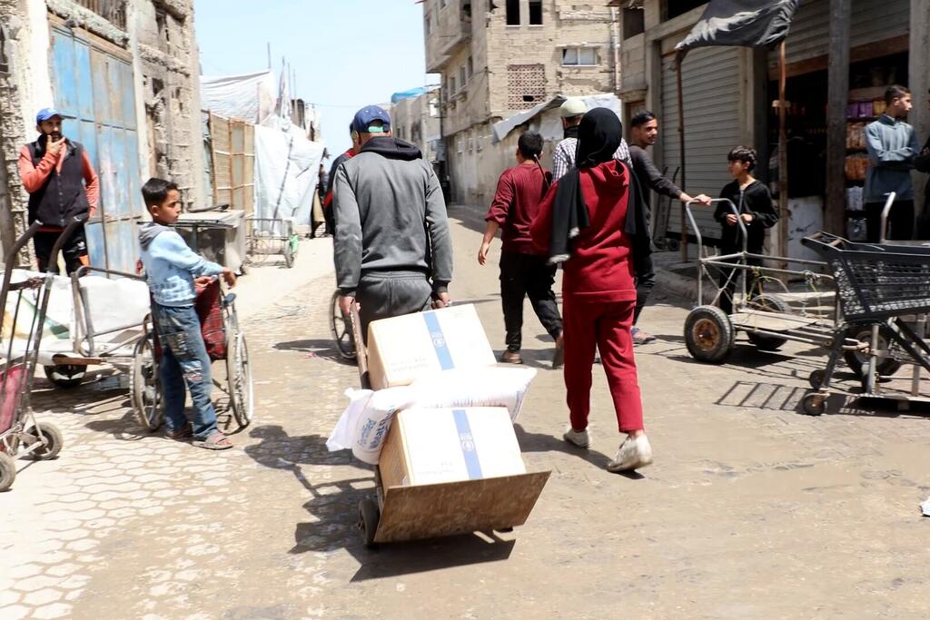 فلسطينيون يتلقون مساعدات غذائية من مركز توزيع للمواد الغذائيى تابع لبرنامج الأغذية العالمي.